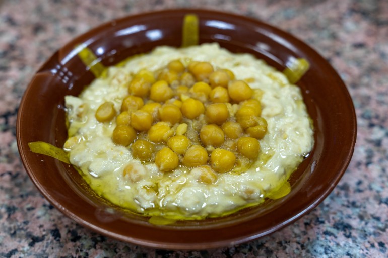 Close-up of a brown bowl of msabaha doused in fruity olive oil