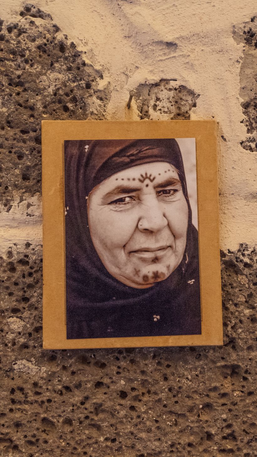 A photo of a photo hanging in Temel’s studio, showing an elderly woman adorning a symbolic sun motif on her forehead.