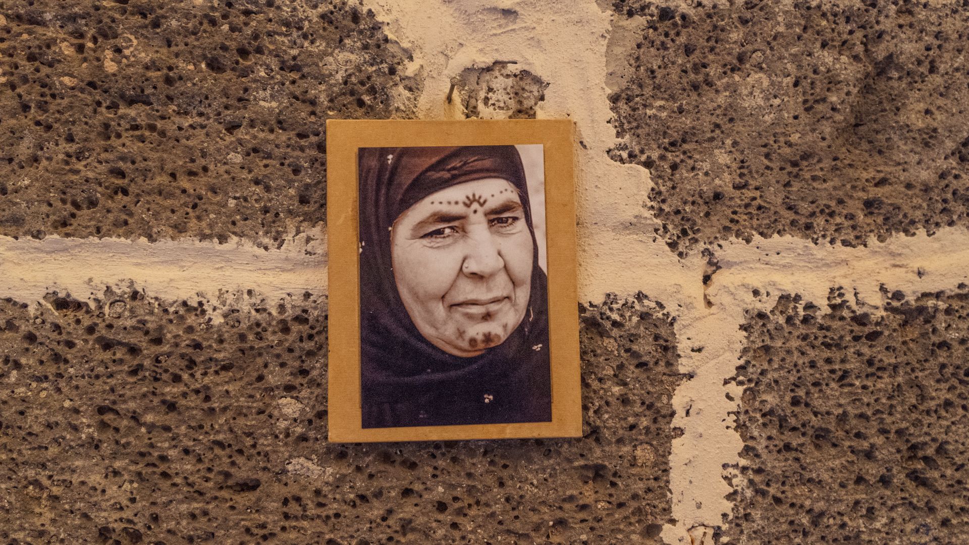 A photo of a photo hanging in Temel’s studio, showing an elderly woman adorning a symbolic sun motif on her forehead.