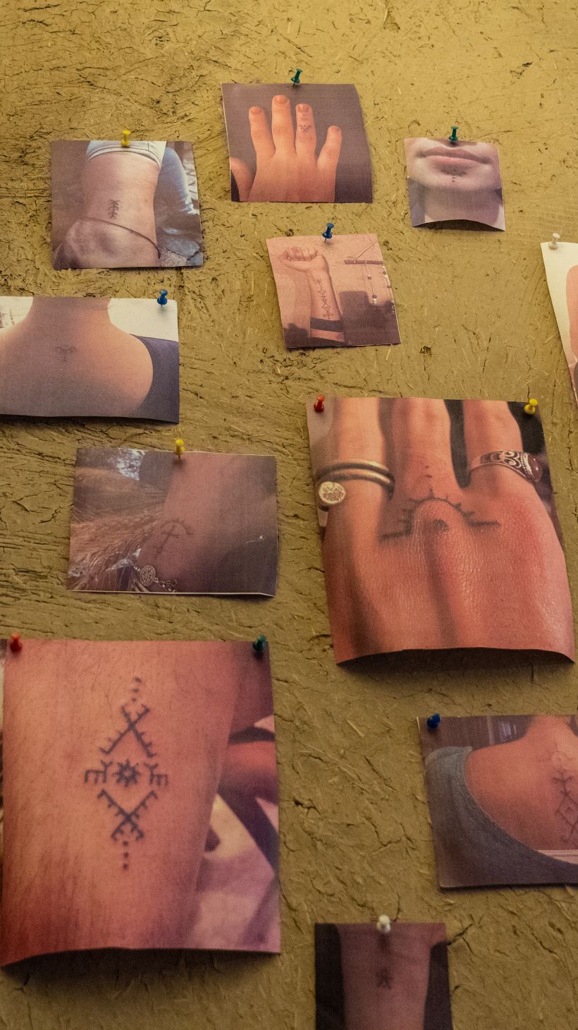 A photo of photos on the walls of a studio, showing traditional deq symbols and motifs