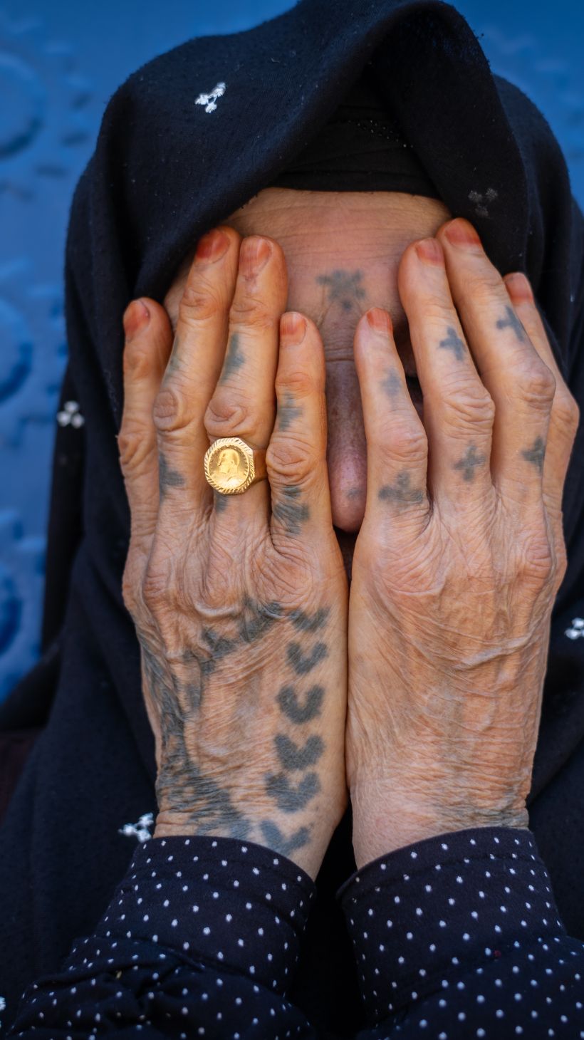 A photo of Fatma Arik, who is in her 70s, with a ladder motif etched across her hands.