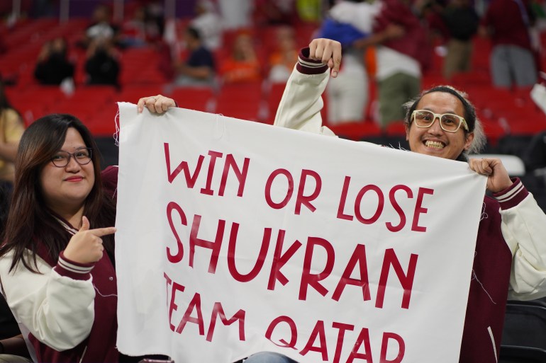 Two fans hold a sign that reads: 'Win or lose Shukran Team Qatar'