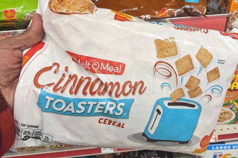 A person holding a packet of Cinnamon Toasters cereal.