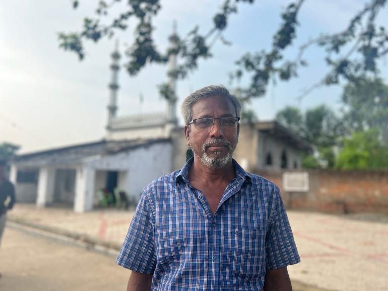 A photo of a man standing in front of a mosque.