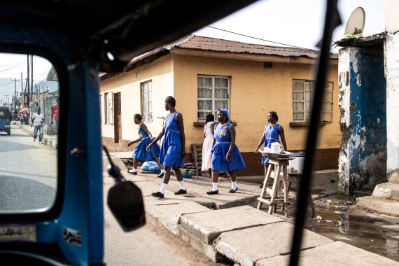 Four school girls make their way to class in Freetown on April 12, 2022. (Photo by JOHN WESSELS / AFP)
