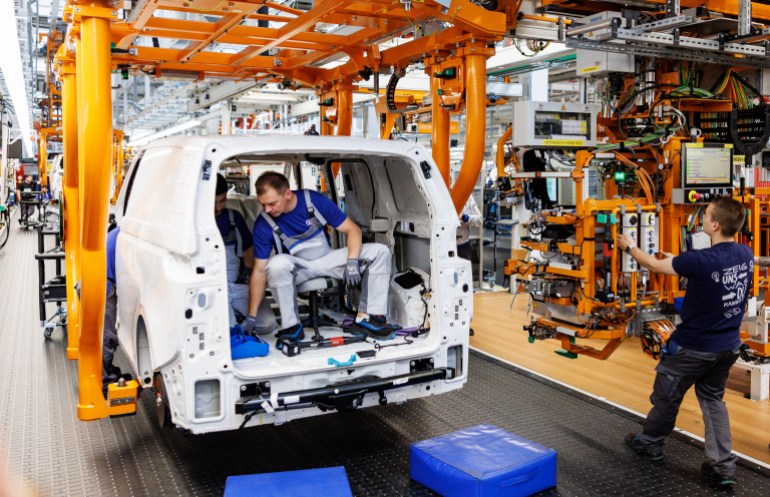Mechanics work at the assembly line of a VW ID Buzz, the new fully electric-driven microbus of Volkswagen Commercial Vehicles, at the Volkswagen plant in Hanover, northern Germany on June 16, 2022. - The company plans to build 130,000 units of the car per year in Hanover. (Photo by Axel Heimken / AFP)