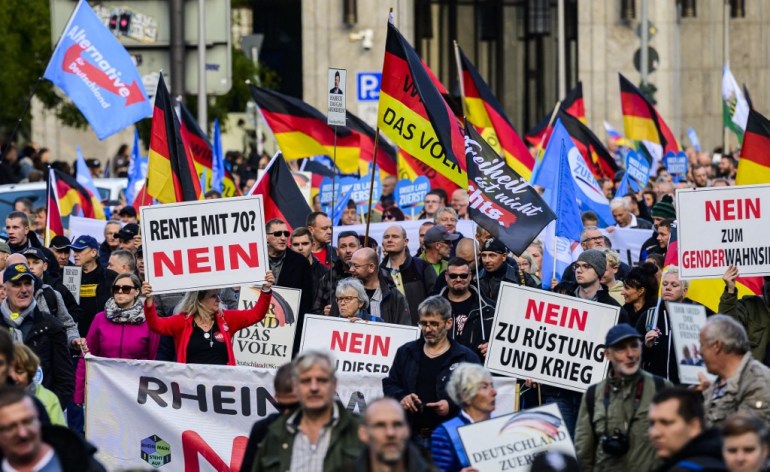 A protester holds up a sign reading: "No to retirement at 70" (L) during a rally of far-right groups including the Alternative for Germany (AfD) party against rising prices in Berlin