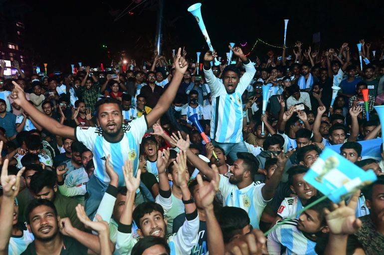 Football fans react as they watch the Qatar 2022 World Cup Group C football match between Poland and Argentina on a big screen.