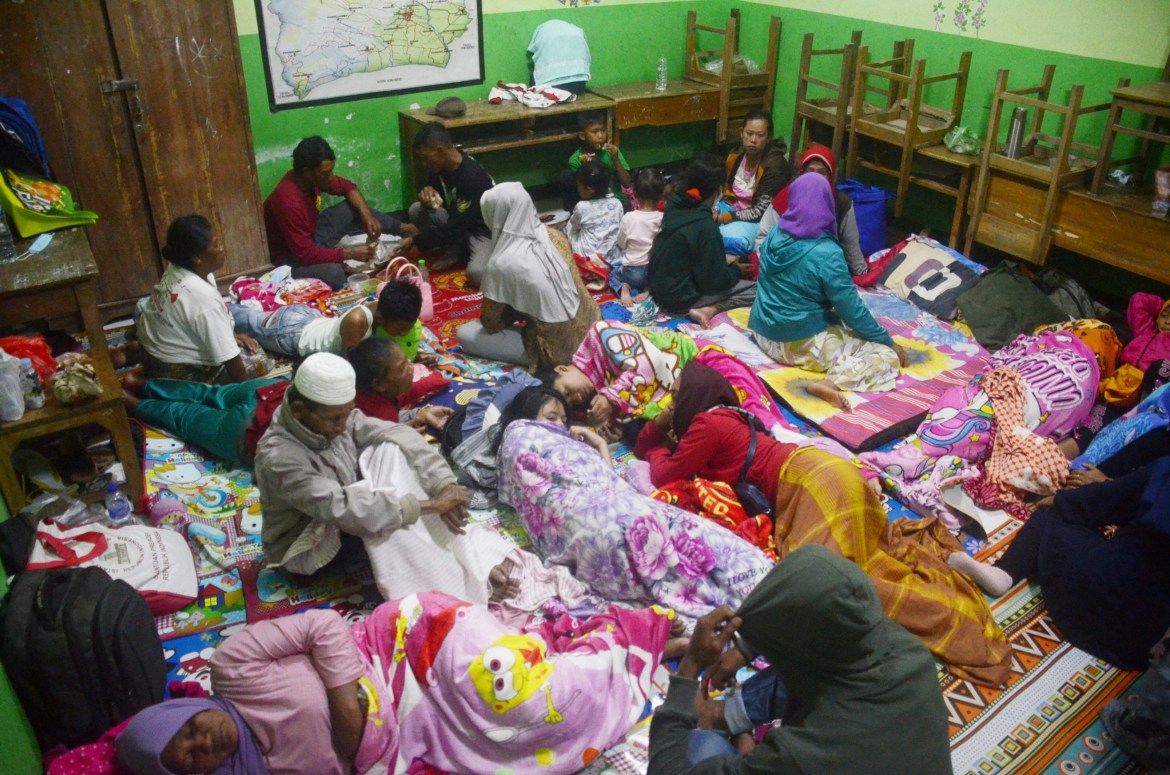 People take temporary shelter in a room at a school following Mount Semeru's volcanic eruption