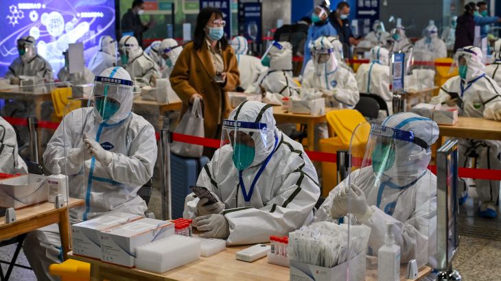 Health workers wait to test passengers for the Covid-19 coronavirus after their arrival at Hongqiao railway station in Shanghai, on December 6, 2022.