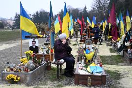 An elderly woman grieves next to the grave of a Ukrainian soldier during Ukraine's Army Day at Lychakiv Cemetery in the western Ukrainian city of Lviv on December 6, 2022, amid the Russian invasion of Ukraine. (Photo by YURIY DYACHYSHYN / AFP)