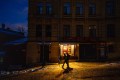 Two men illuminated by lights from a shop on an otherwise dark street in Kyiv