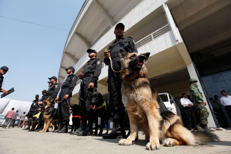 Members of Rapid Action Battalion (RAB) stand guard with dogs in front of a stadium in Dhaka