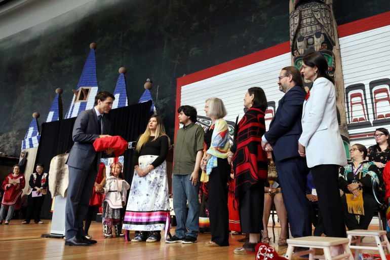 Justin Trudeau receives a ceremonial copy of an inquiry into murdered and missing Indigenous girls and women as representatives look on