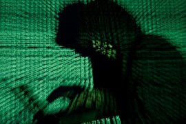 A stylised photo showing a fuzzy silhouette of a person at a laptop with green code projected over them.