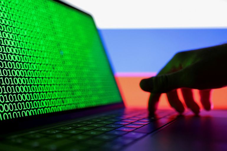 A hand is seen on a laptop with binary code displayed on the screen in front of Russian flag in this picture illustration taken August 19, 2022. REUTERS/Dado Ruvic/Illustration