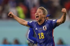 Japan's Takuma Asano with his mouth open, his face excited and his arms out