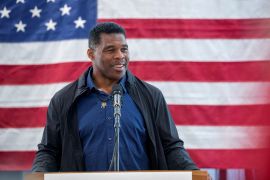 Republican US Senate candidate Herschel Walker speaks at a lectern in front of a large US flag during a campaign stop in Ellijay, Georgia.