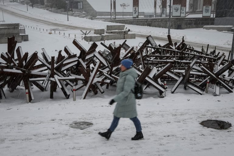 A woman walks down a street near anti-tank constructions amid a snowfall as Russia's invasion of Ukraine continues, in central Kyiv, Ukraine December 7, 2022.