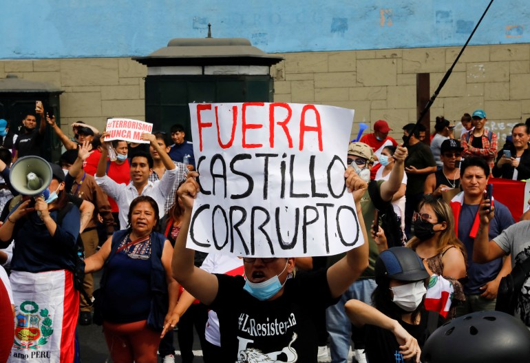 People hold signs while protesting against Castillo