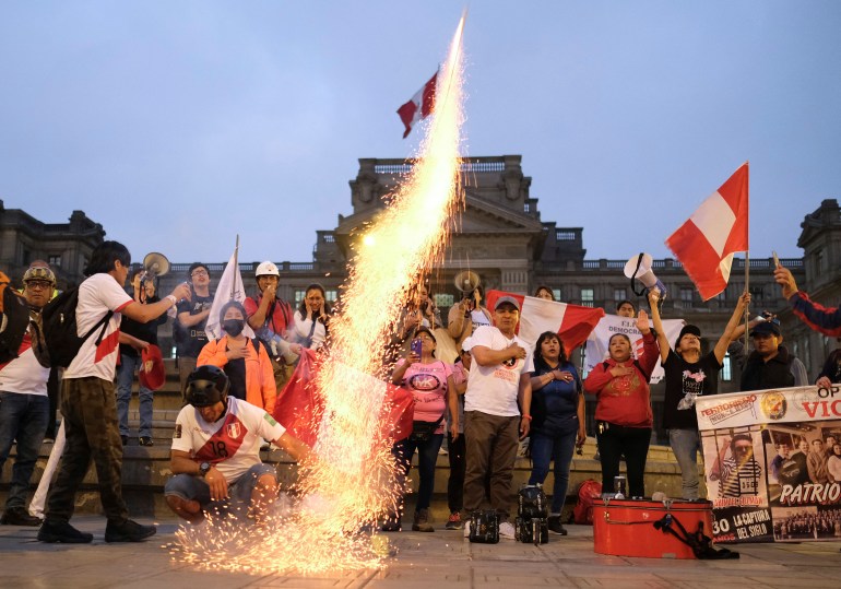 A man lights a firework as people hold up Peru's flags, after Congress approved the removal of President Pedro Castillo, in Lima, Peru, December 7, 2022. REUTERS/Liz Tasa
