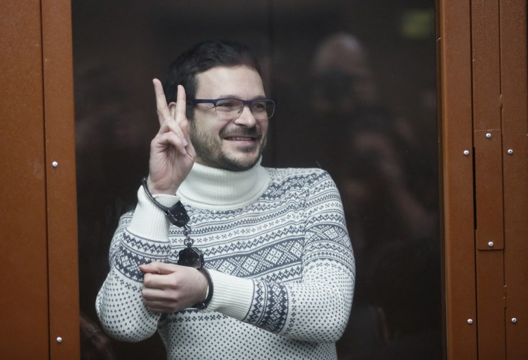 Ilya Yashin holds up a peace sign in a defendant's glass cage