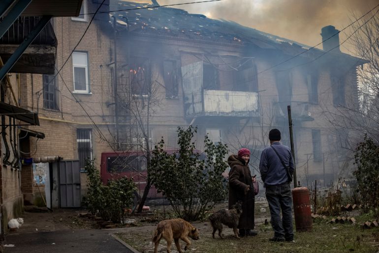 Residents stand in the yard of their destroyed apartment building looking at the smoke rise in Bakhmut, Ukraine.
