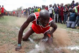A Maasai Moran falls after throwing a javelin as he competes in a social sporting event dubbed the Maasai Olympics.