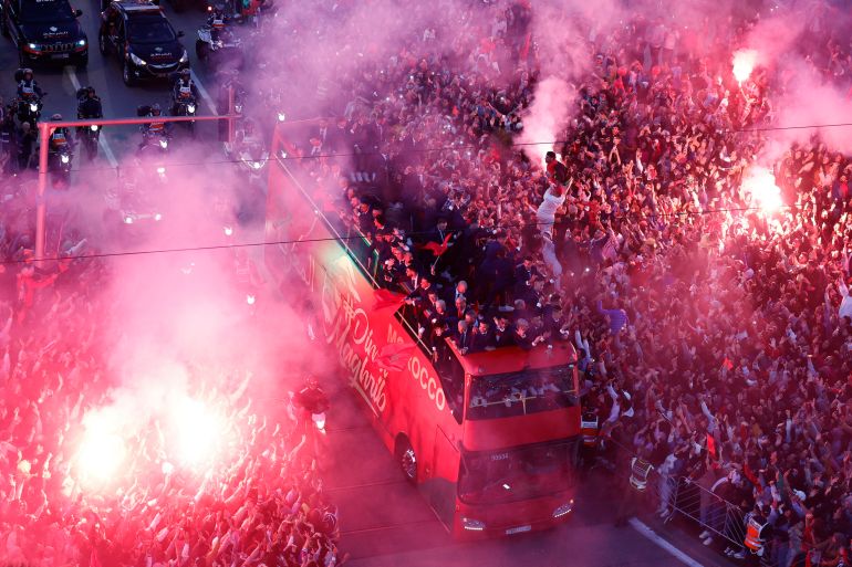 Fans celebrate with flares as Morocco players arrive on a bus