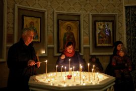 A man lights a candle during a service on the eve of Christmas, amid Russia's attack on Ukraine in Kyiv.