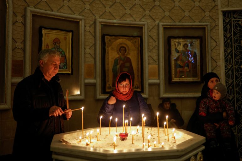 A man lights a candle during a service on the eve of Christmas, amid Russia's attack on Ukraine in Kyiv.