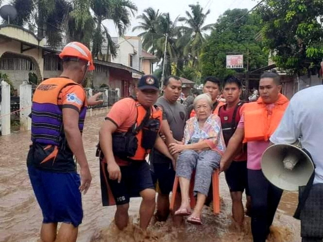 Rescue workers helps a resident affected by floods, in Plaridel, Misamis Occidental Province, Philippines, December 26, 2022. Philippine Coast Guard/Handout via REUTERS THIS IMAGE HAS BEEN SUPPLIED BY A THIRD PARTY. MANDATORY CREDIT. NO RESALES. NO ARCHIVES