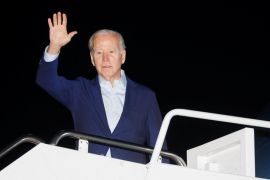 Biden waves from the steps of an airplane
