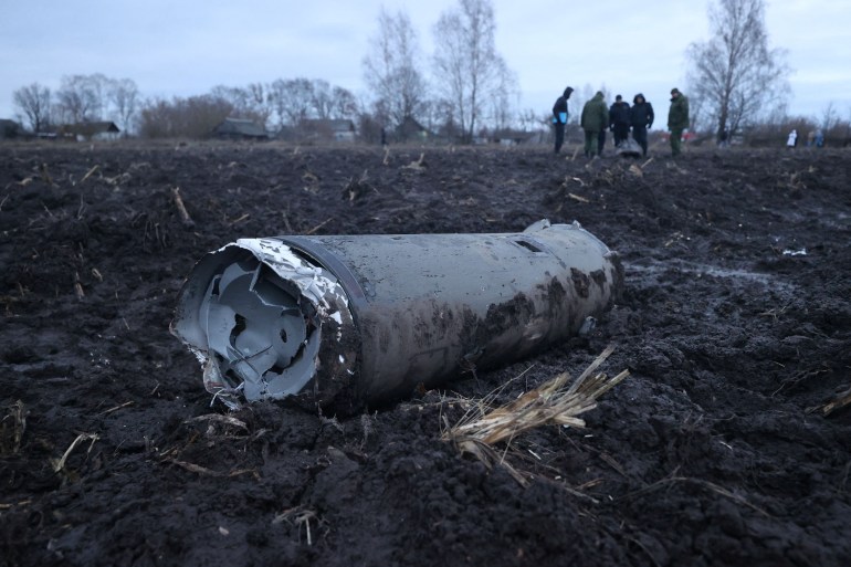 Investigators gather near a fragment of a munition, what Belarus' defence ministry said was part of a Ukrainian S-300 missile