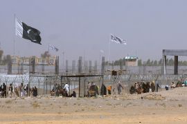 FILE - Pakistan and Taliban flags flutter on their respective sides while people walk through a security barrier to cross border at a key border crossing point between Pakistan and Afghanistan, in Chaman, Pakistan, Aug. 18, 2021. The Taliban win in Afghanistan gave a boost to militants in neighboring Pakistan. Faced with rising violence, Pakistan is taking a tougher line to pressure Afghanistan’s Taliban rulers to crack down on militants hiding on their soil, but so far the Taliban remain reluctant to take action -- trying instead to broker a peace. (AP Photo/Jafar Khan, File)