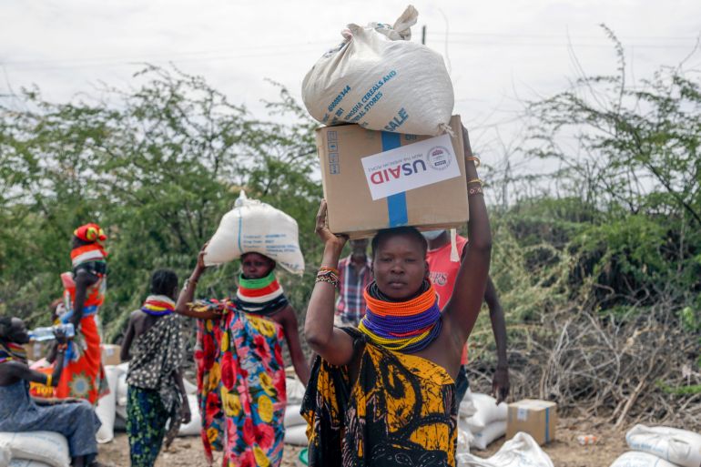 Locals carry boxes and sacks of food distributed by USAID in Kachoda, northern Kenya, July 23, 2022