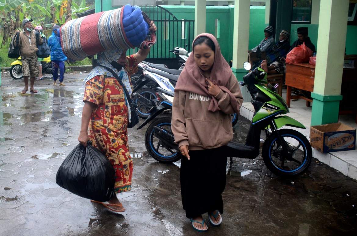 People carry their belongings as they arrive at a school turned into temporary shelter