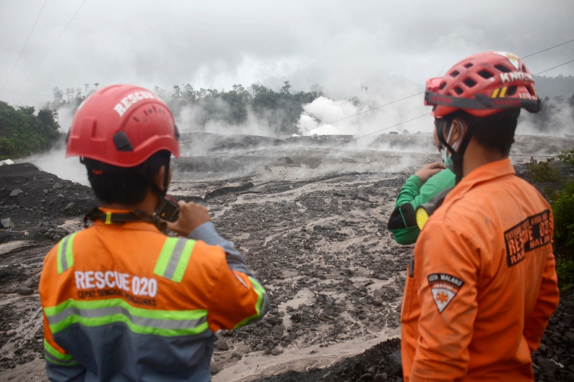 Rescuers monitor the flow of volcanic materials