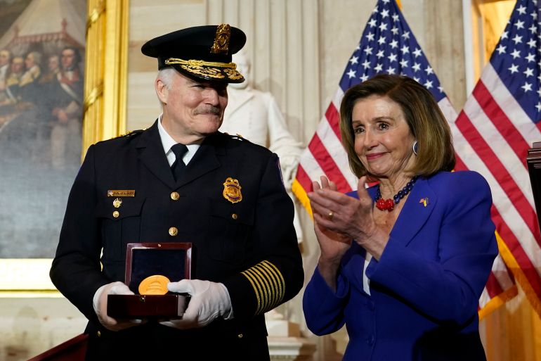 A police officer holds a Congressional Gold Medal as Nancy Pelosi claps