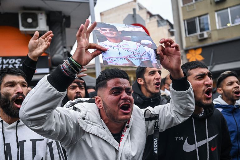 Relatives and other protesters from the Roma community chant slogans outside the courthouse in Greece's second largest city of Thessaloniki, holding up photos of an injured 16-year-old and calling for justice