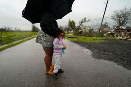 Trinity Allen, 4, stands in the rain with her grandmother after they came to help friends whose home was destroyed from a tornado