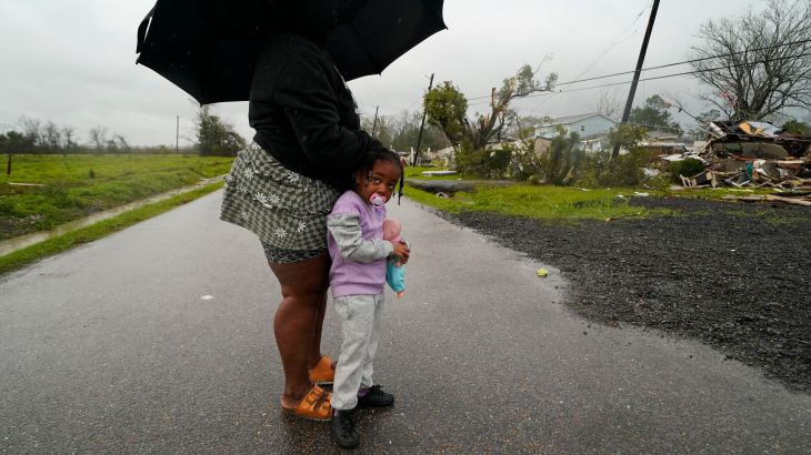 Trinity Allen, 4, stands in the rain with her grandmother after they came to help friends whose home was destroyed from a tornado