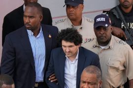 FTX founder Sam Bankman-Fried is escorted out of a court following a hearing in Nassau, Bahamas.