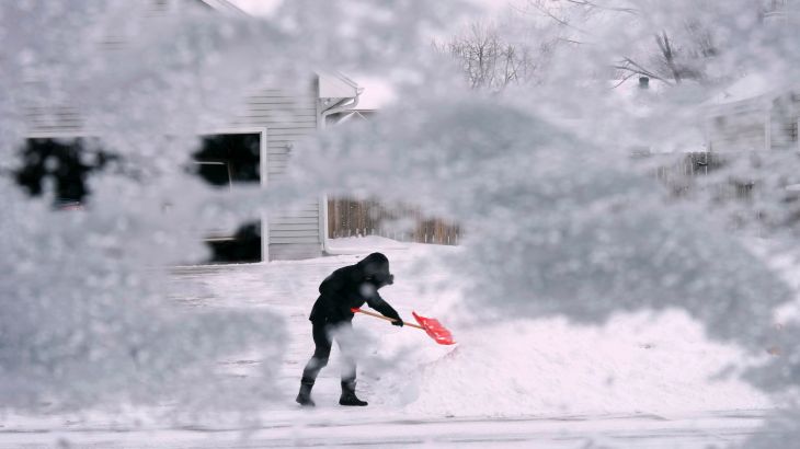 A local resident shovels snow off the end of a driveway