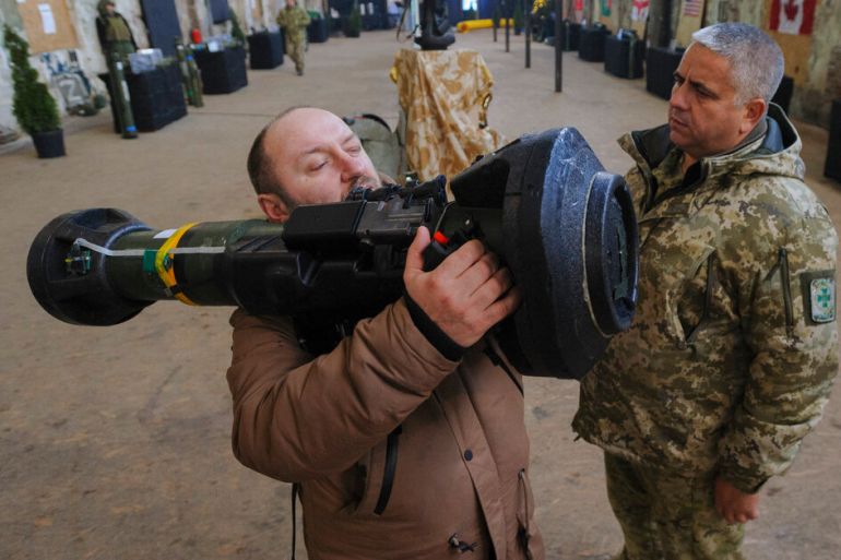 A Ukrainian service member shows a civilian how to operate an anti-tank weapon during the Weapon of Victory exhibition in Lviv, western Ukraine.