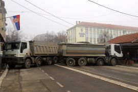 A man passes by a barricade made of trucks loaded with stones that was erected in the town of Mitrovica, northern Kosovo