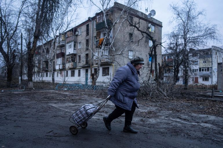 A local woman walks to the distribution point of humanitarian aid in front of housing which was damaged by Russian shelling in Kupiansk, Kharkiv region, Ukraine, Wednesday, Dec. 28, 2022. (AP Photo/Evgeniy Maloletka)