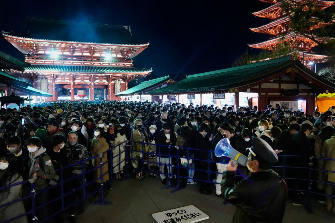 A police officer speaks on a megaphone to control a crowd of people as they wait in queue before they pray at the main hall of Sensoji Buddhist temple on New Year's Day in Tokyo.