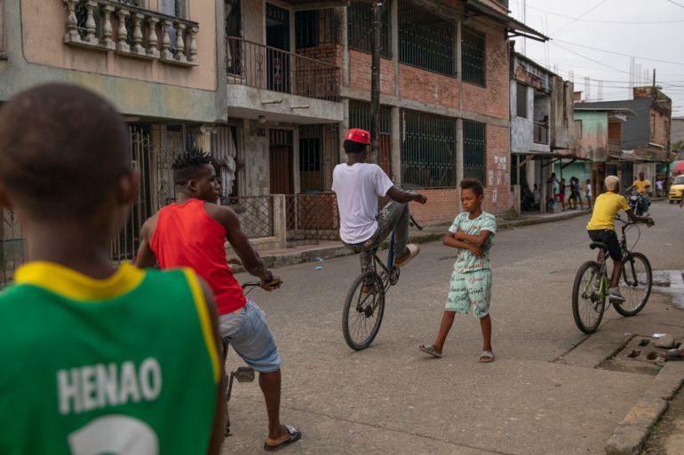 Kids play in the streets of Buenaventura, one showing off how to do a "wheelie" on his bike