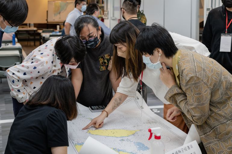 A group of four women checking a nautical chart of Taiwan island as part of a civil defence course. They look very intent on what they're doing